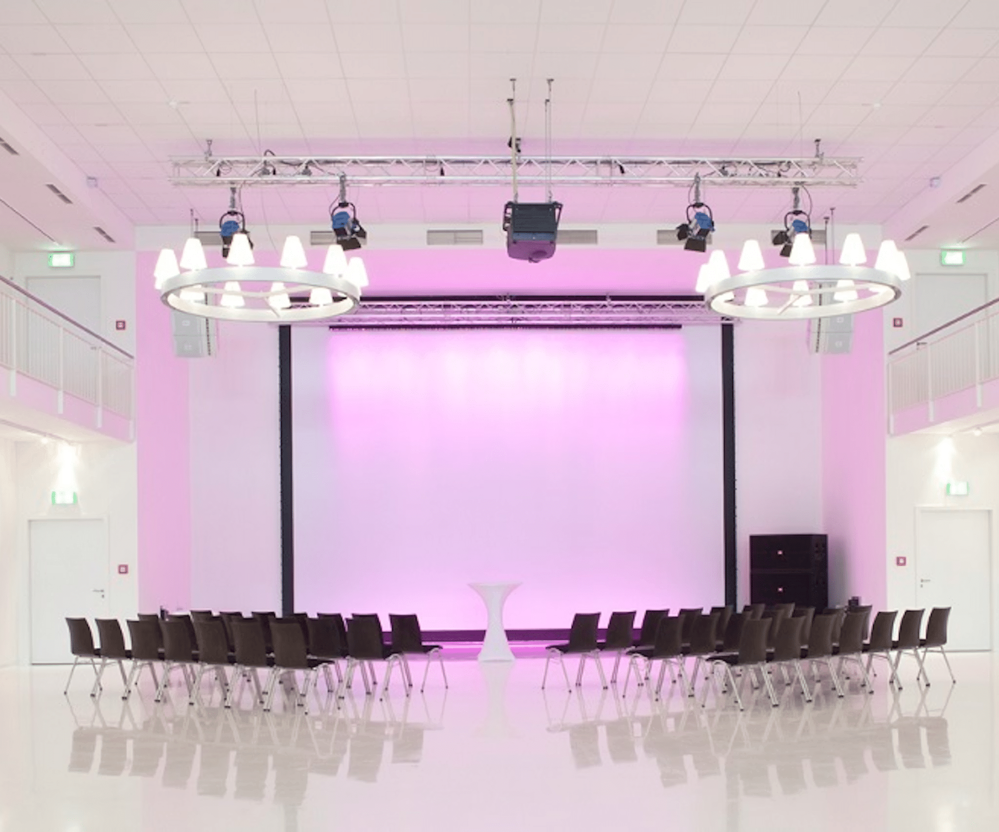 Moderner Konferenzraum mit rosa Beleuchtung, Stuhlreihen und Podium, ideal für HK Consultings Digitalisierungsseminar.