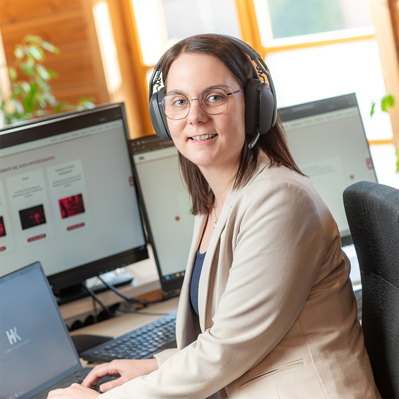 Mitarbeiterin von HK Consulting arbeitet am Computer mit Headset, Dokumente-Digitalisierung und Content-Management im Büro.